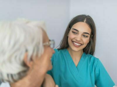 Young experienced doctor and older female patient. Image of elderly woman having professional medical care. Smiling senior woman and her young pretty caregiver