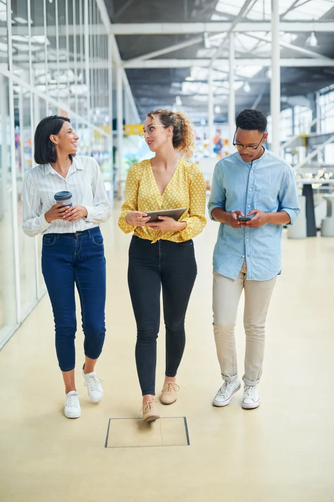 group of 3 diverse young professionals walking in a modern office together